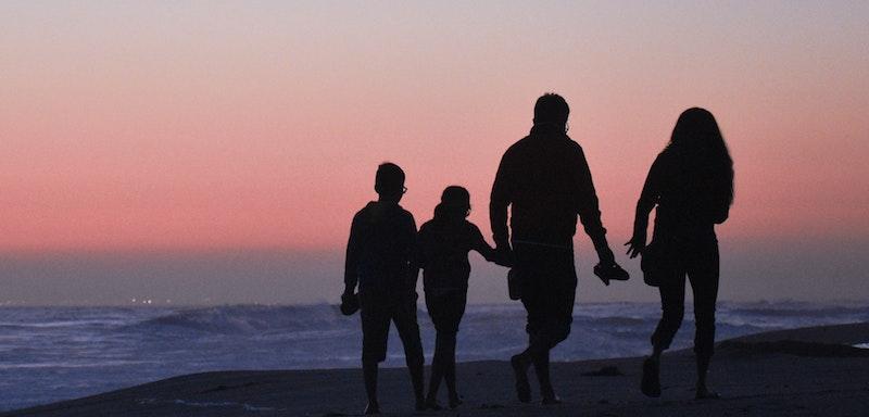 Family walking on beach at sunset